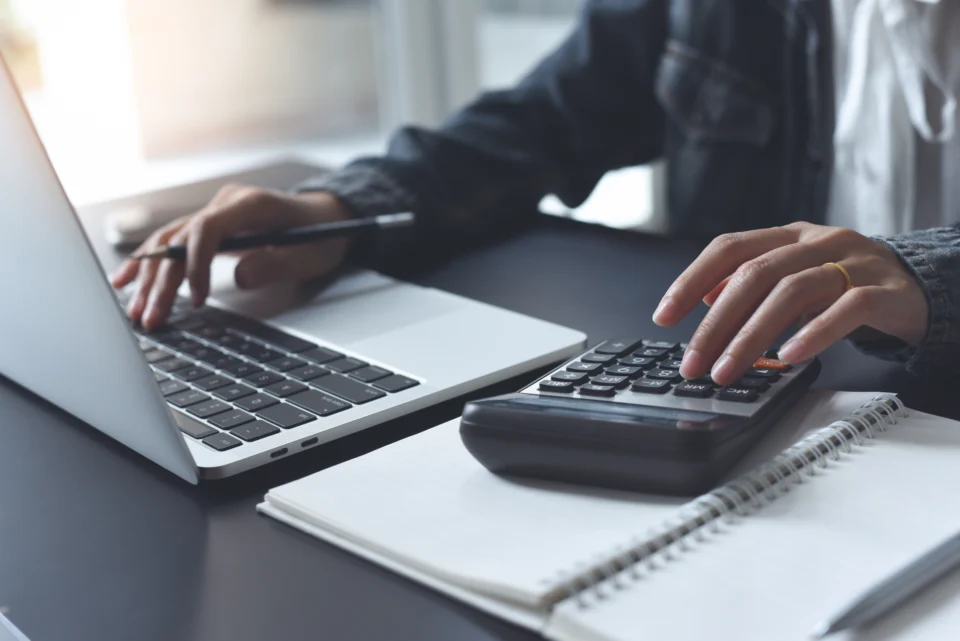 Homme qui travaille sur son ordinateur et avec sa calculatrice