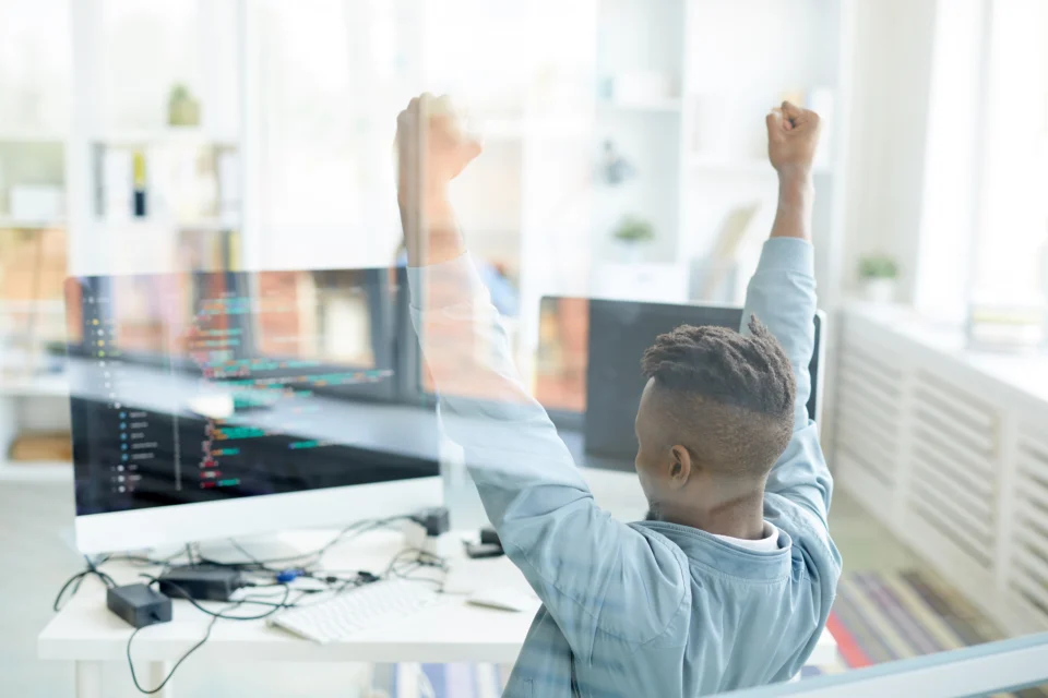 D&eacute;veloppeur content devant plusieurs &eacute;crans