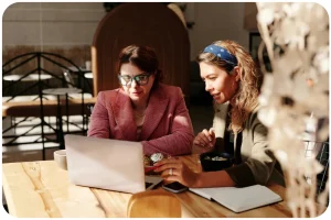 Deux femmes assis et travaillant sur un ordinateur portable.